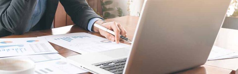 Przedsiębiorca analizuje na laptopie raport BIK swojej firmy pobrany online